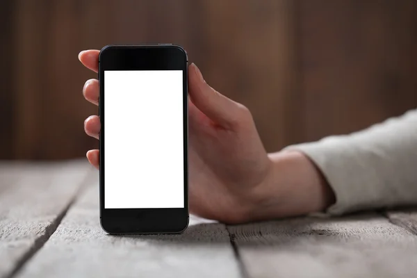 Smart telefon och flicka håller den över ett träbord — Stockfoto