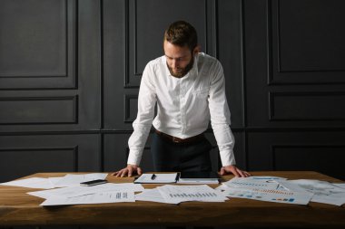 Bir dizüstü bilgisayar kullanarak bir pencerenin yanındaki ofiste çalışan adam