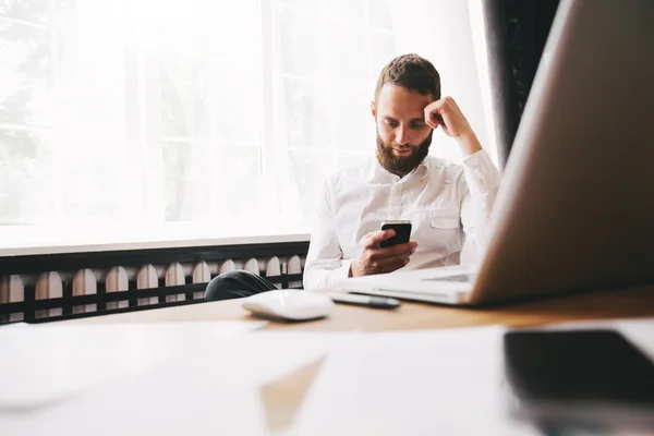 Mann arbeitet im Büro neben einem Fenster mit einem Laptop — Stockfoto