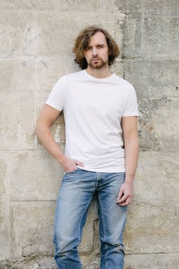 Hipster yakışıklı erkek manken beyaz boş tişört giyiyor. Logonuz için yeri var. Ya da Avrupa sokaklarında gelişigüzel tasarlanmış.