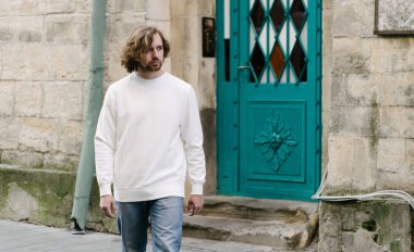 Beyaz sweatshirt ya da kapüşonlu bir adam Avrupa sokaklarında boş yeri olan logo tasarımları ya da tasarım baskıları yapıyor..