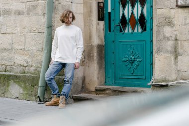 Beyaz sweatshirt ya da kapüşonlu bir adam Avrupa sokaklarında boş yeri olan logo tasarımları ya da tasarım baskıları yapıyor..