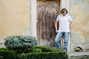 Hipster yakışıklı erkek manken beyaz boş tişört giyiyor. Logonuz için yeri var. Ya da Avrupa sokaklarında gelişigüzel tasarlanmış.