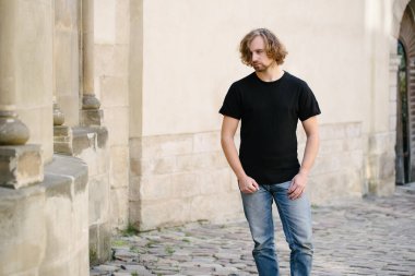 Hipster yakışıklı erkek manken siyah boş tişört giyiyor. Logonuz için yeri var. Ya da Avrupa sokaklarında gelişigüzel tasarlanmış.