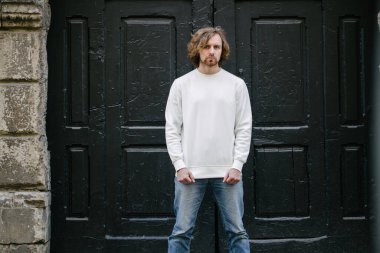 Beyaz sweatshirt ya da kapüşonlu bir adam Avrupa sokaklarında boş yeri olan logo tasarımları ya da tasarım baskıları yapıyor..