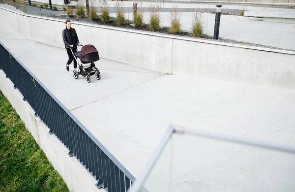 Mother with a pram or stroller on modern city streets walking and relaxing in autumn