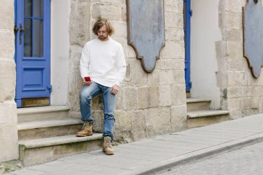 Beyaz sweatshirt ya da kapüşonlu bir adam şehrin sokaklarında boş yeri olan logo tasarımları ya da tasarım baskıları yapıyor..