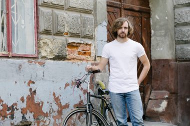 Hipster yakışıklı erkek manken beyaz boş tişört giyiyor. Logonuz için yeri var. Ya da Avrupa sokaklarında gelişigüzel tasarlanmış.