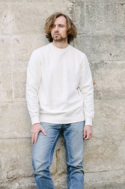 Beyaz sweatshirt ya da kapüşonlu bir adam şehrin sokaklarında boş yeri olan logo tasarımları ya da tasarım baskıları yapıyor..