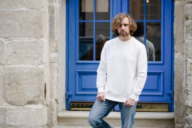 Beyaz sweatshirt ya da kapüşonlu bir adam şehrin sokaklarında boş yeri olan logo tasarımları ya da tasarım baskıları yapıyor..