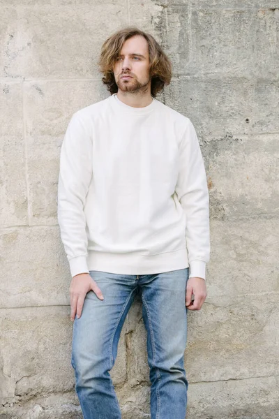 Man wearing white sweatshirt or hoodie for mock up, logo designs or design prints with with free space on the city streets.