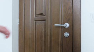 Metal kapı koluyla ahşap kapıyı açan kadın. 