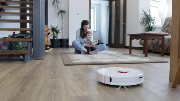 Robotdammsugare Ett Vardagsrum Medan Mamma Och Ett Barn Leker Inomhus — Stockvideo