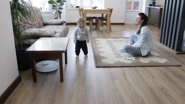 Robot Stofzuiger Schoonmaken Een Woonkamer Terwijl Moeder Een Kind Spelen — Stockvideo