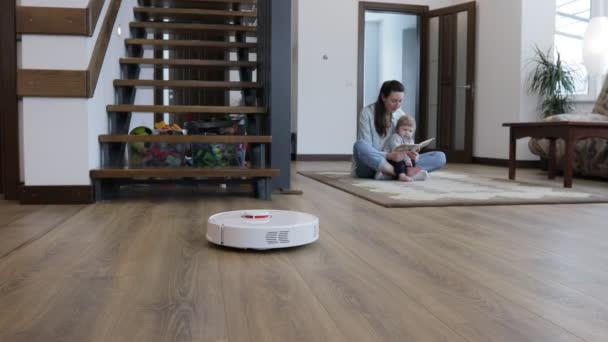 Robotdammsugare Ett Vardagsrum Medan Mamma Och Ett Barn Leker Inomhus — Stockvideo