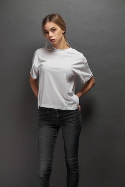 Logonuz için yeri olan beyaz, boş tişört giyen kadın, gri arkaplan üzerinde tasarım veya maket yapın
