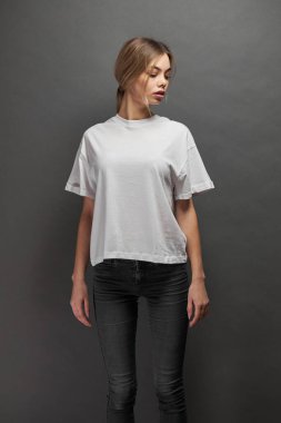 Logonuz için yeri olan beyaz, boş tişört giyen kadın, gri arkaplan üzerinde tasarım veya maket yapın