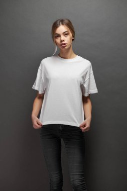 Logonuz için yeri olan beyaz, boş tişört giyen kadın, gri arkaplan üzerinde tasarım veya maket yapın