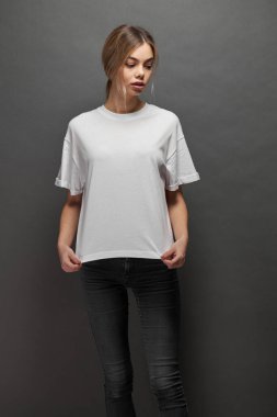 Logonuz için yeri olan beyaz, boş tişört giyen kadın, gri arkaplan üzerinde tasarım veya maket yapın