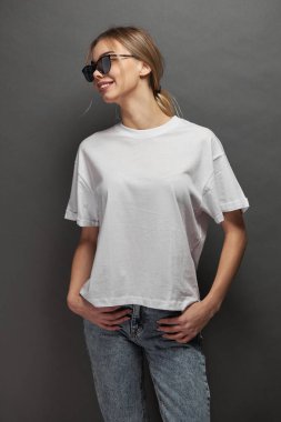 Logonuz için yeri olan beyaz, boş tişört giyen kadın, gri arkaplan üzerinde tasarım veya maket yapın