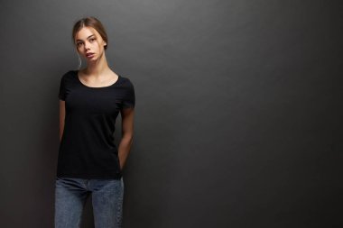 Logonuz için yeri olan siyah, boş tişört giyen bir kadın, gri arka plan üzerinde gelişigüzel kentsel tarzda tasarlayın ya da tasarlayın