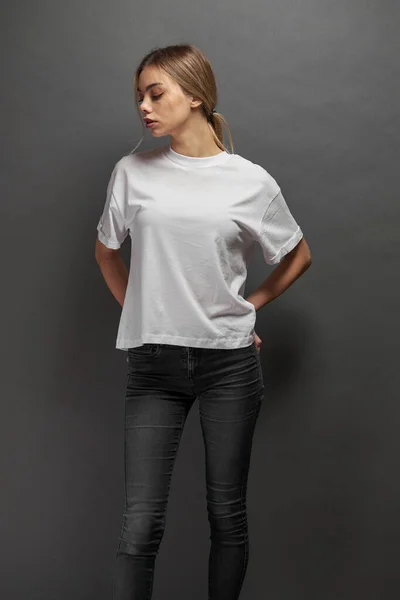 Woman wearing white blank t-shirt with space for your logo, mock up or design over gray background