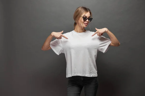 Woman wearing white blank t-shirt with space for your logo, mock up or design over gray background