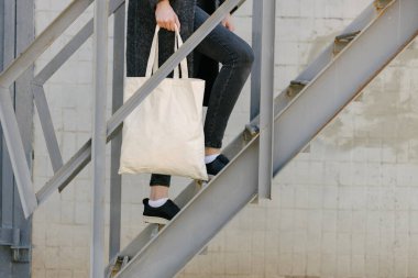 Kentsel alanda beyaz tekstil çantalı bir kadın. Ekoloji ya da çevre koruma kavramı. Model için beyaz eko çanta.