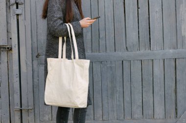 Kentsel alanda beyaz tekstil çantalı bir kadın. Ekoloji ya da çevre koruma kavramı. Model için beyaz eko çanta.
