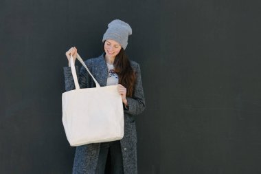 Kentsel alanda beyaz tekstil çantalı bir kadın. Ekoloji ya da çevre koruma kavramı. Model için beyaz eko çanta.