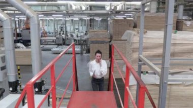 Marangoz fabrikasındaki iş kadını tablet bilgisayar kullanıyor. Marangozluk fabrikası. Parke tahtası üretimi için bir fabrika