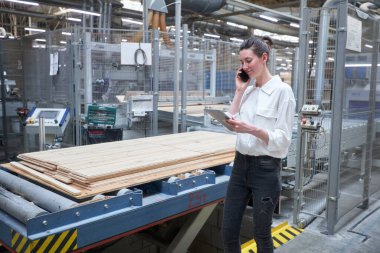 Marangoz fabrikasında tablet bilgisayar kullanan bir kadın işçi. Marangozluk fabrikası. Parke tahtası üretimi için bir fabrika