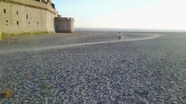 Sevgili bir çift, Fransa 'nın Normandiya, alacakaranlıkta güzel bir alacakaranlıkta Le Mont Saint-Michel gelgit adasının yanında yürüyor..