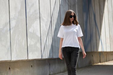 Kız ya da kadın, logonuz için yeri olan beyaz, boş tişörtler giyiyor, şehir tarzı modeller yapıyor ya da tasarlıyor.