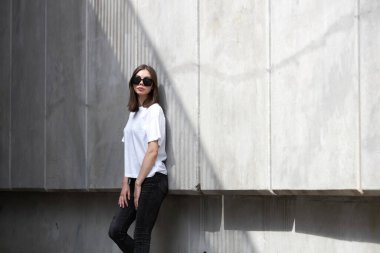 Kız ya da kadın, logonuz için yeri olan beyaz, boş tişörtler giyiyor, şehir tarzı modeller yapıyor ya da tasarlıyor.