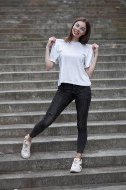 Kız ya da kadın, logonuz için yeri olan beyaz, boş tişörtler giyiyor, şehir tarzı modeller yapıyor ya da tasarlıyor.