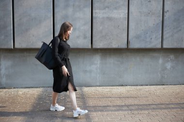 Sexy business brunette woman with a make up wearing black clothes She is walking on city cement streets