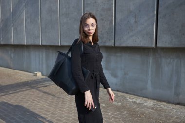 Sexy business brunette woman with a make up wearing black clothes She is walking on city cement streets