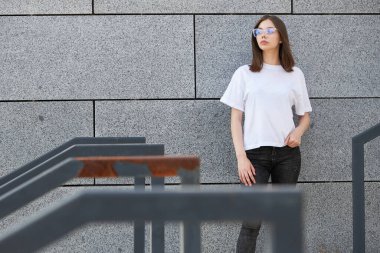 Kız ya da kadın, logonuz için yeri olan beyaz, boş tişörtler giyiyor, şehir tarzı modeller yapıyor ya da tasarlıyor.