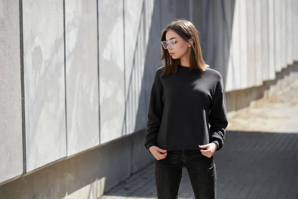 街の通りに無料のスペースとモックアップ ロゴデザインやデザインプリントのための黒いスウェットシャツやパーカーを身に着けている女性 — ストック写真