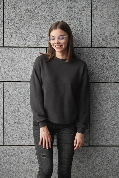 Woman wearing black sweatshirt or hoodie for mock up, logo designs or design prints with with free space on the city streets.