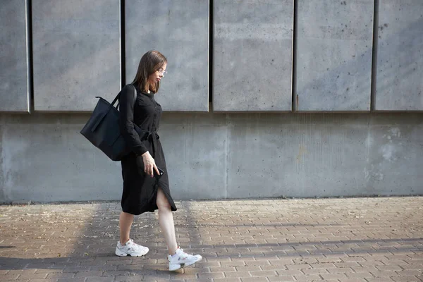 Sexy business brunette woman with a make up wearing black clothes She is walking on city cement streets