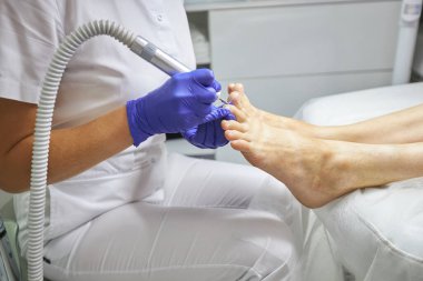 Güzellik salonunda pedikür SPA prosedürü uygulanıyor. Pedikür için elektrikli cihaz. Ayaklarını kaplıcaya sokan kadın.