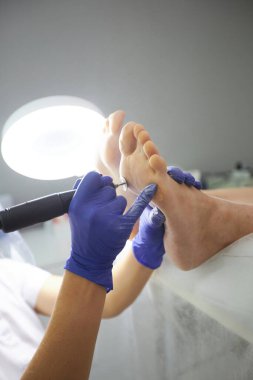 Güzellik salonunda pedikür SPA prosedürü uygulanıyor. Pedikür için elektrikli cihaz. Ayaklarını kaplıcaya sokan kadın.