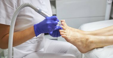 Güzellik salonunda pedikür SPA prosedürü uygulanıyor. Pedikür için elektrikli cihaz. Ayaklarını kaplıcaya sokan kadın.