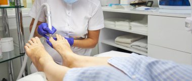 Güzellik salonunda pedikür SPA prosedürü uygulanıyor. Pedikür için elektrikli cihaz. Ayaklarını kaplıcaya sokan kadın.