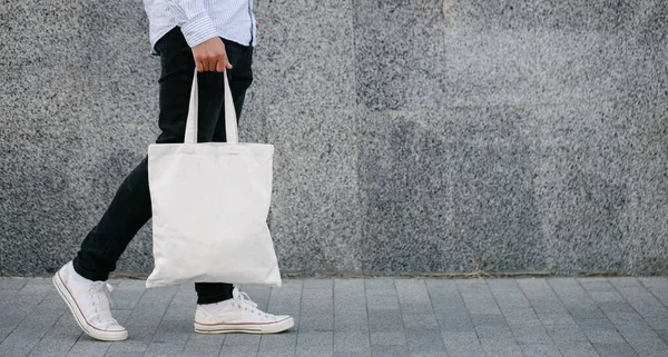 White textile eco tote bag against urban city background. White shopping bag mock up.