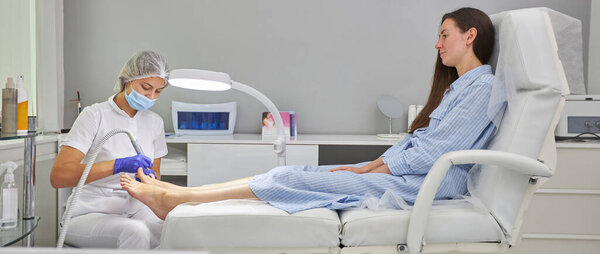 Педикюр SPA процедура в салоне красоты. Электрический прибор для педикюра. Женщине чистят ноги в спа-центре