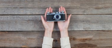 Ahşap masa üzerinde bir retro kamera tutan el