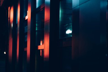 Bir binanın karanlık metal parçası. Dışarısı neon ışıklarla kaplı.